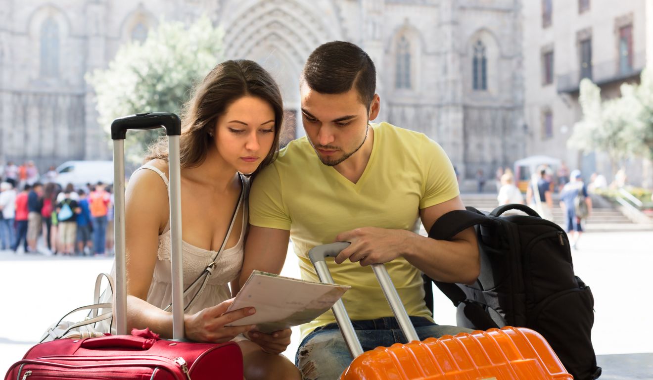 Casal consultando um mapa ao lado de malas de viagem.