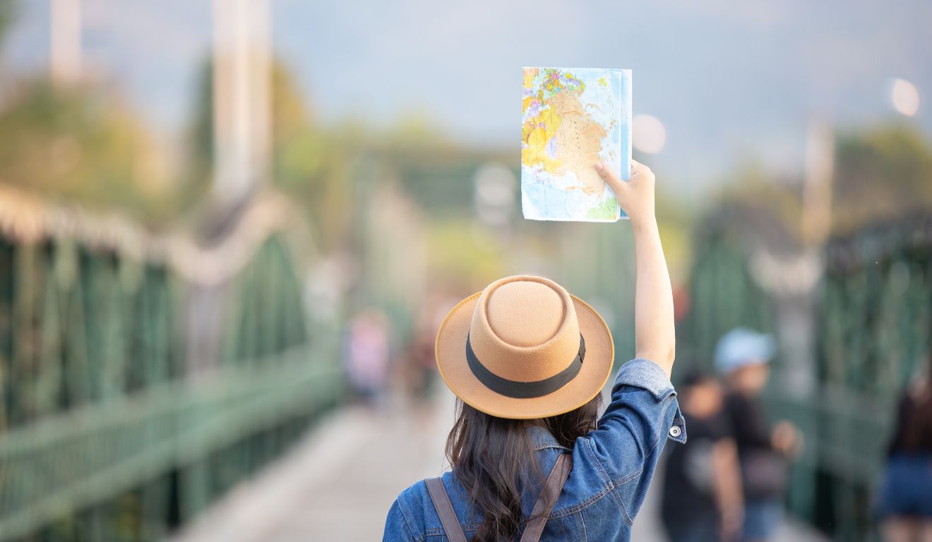 Imagem mostra mulher levantando um mapa enquanto está na Europa