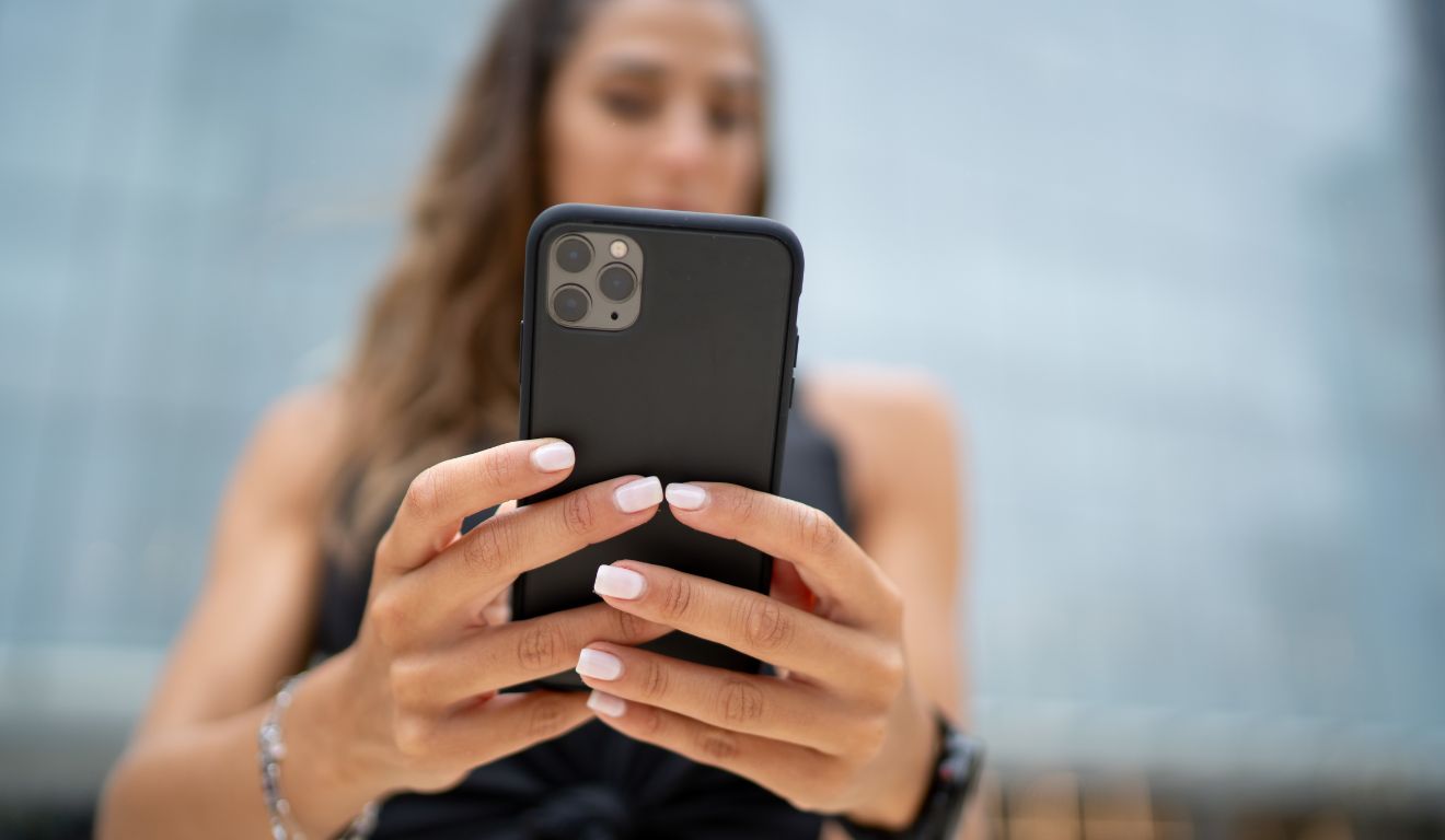 Pessoa segurando um celular com as duas mãos.